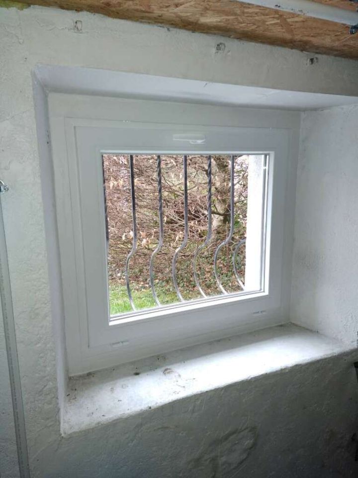 Fenêtre de cave en PVC blanc avec grille de protection